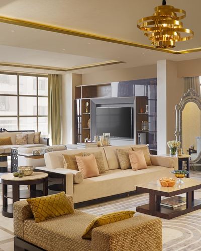 Opulent gold and cream living room with sculptural chandelier and ornate mirror
