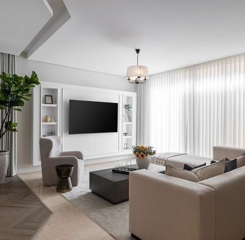 Neutral minimalist living room with white TV wall unit, beige sofas, sheer curtains and herringbone wood floor accent