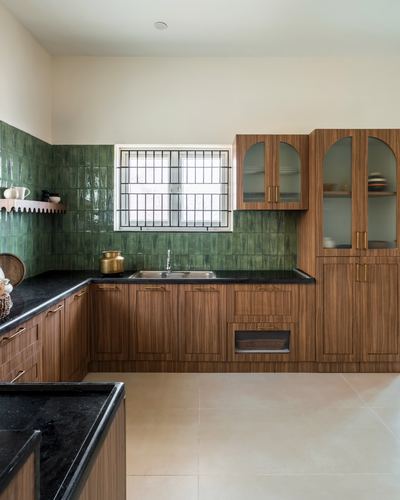 L-shaped wood kitchen with green tile backsplash and arched glass cabinets