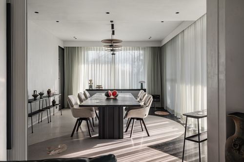 Dining room with marble-top table, cane-style chairs, and sheer curtains diffusing daylight