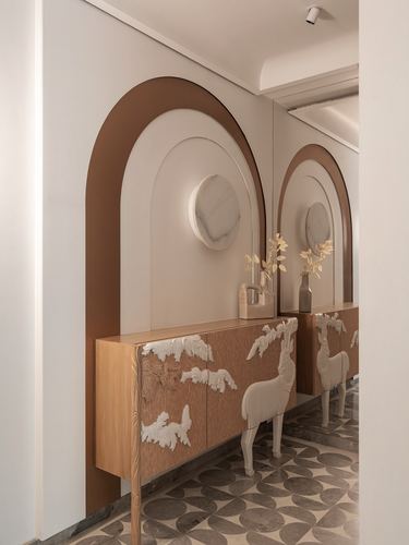Arched niche with stone disc above a wood console with sculpted deer relief in a foyer