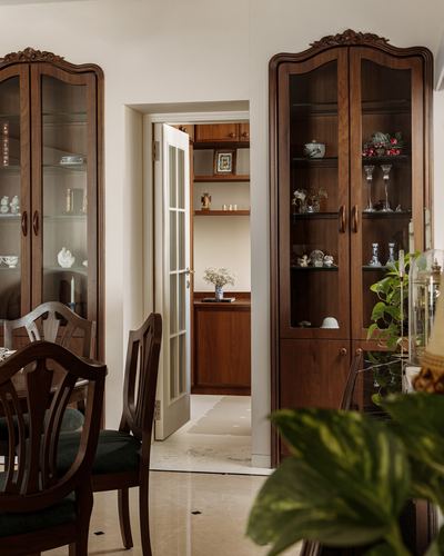 Two carved wood display cabinets flank a doorway into a study nook in a dining room