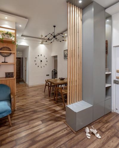 Foyer with wood-slat partition, grey storage unit, and dining area beyond on wood-look floor
