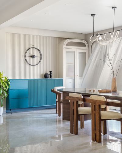 Dining area with teal fluted sideboard, wood table, and sheer draped canopy over chairs
