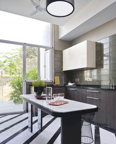 Kitchen with striped marble floor, dark cabinetry, olive tiled backsplash and marble-top island