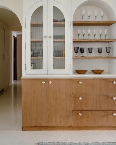 Arched built-in cabinet with fluted glass doors and open shelves displaying glassware, wood cabinetry below