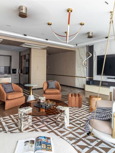 Living room with terracotta armchairs, marble flooring, sculptural brass pendant, and a swing chair