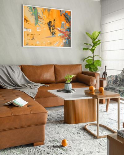 Living room with tan leather sectional, fluted coffee table, and bold abstract art above