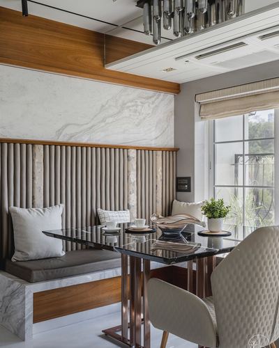 Dining nook with tufted banquette, marble wall, wooden trim, black marble table by window
