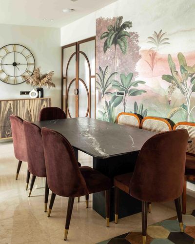 Dining room with black marble table, burgundy velvet chairs, and a botanical mural wall