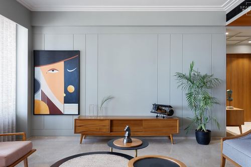 Grey paneled living room wall with wooden console, framed portrait art, and potted palm