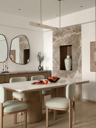 Dining room with marble table, sage chairs, and stone-clad wall niche