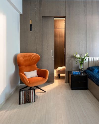 Orange velvet armchair beside wood-paneled wall with sliding door to bedroom, Nagpur home