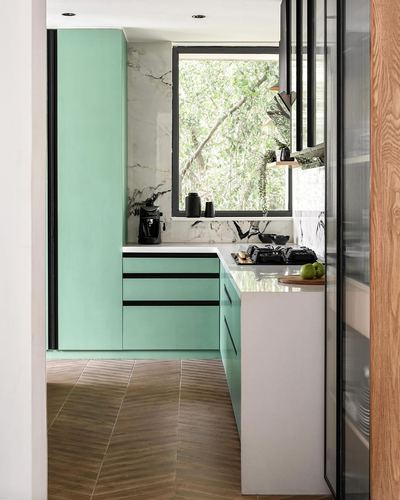 Mint-green kitchen with marble backsplash, large window and herringbone wood floor viewed through doorway