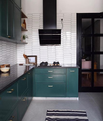 Green kitchen with white hexagonal tile backsplash, black countertop and chimney hood, Chennai
