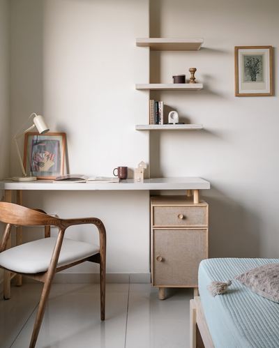 Study nook with wooden desk, cane cabinet, floating shelves and framed art