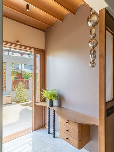 Entryway with scalloped wood ceiling, floating wood console, and bubble glass pendant light