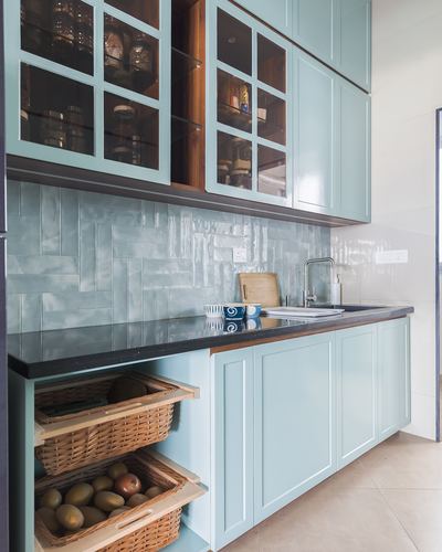 Sage green kitchen with glass-front cabinets, dark countertop, herringbone tile backsplash and wicker produce baskets