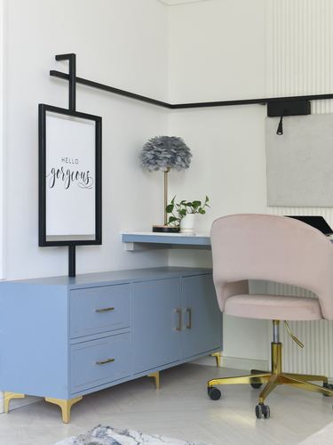 Blue cabinet desk nook with pink velvet office chair and feathered lamp under framed print