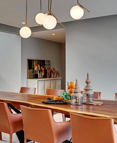 Live-edge wood dining table with tan leather chairs under globe pendant lights