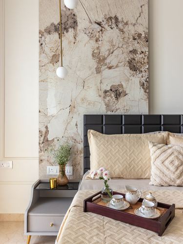 Bedroom corner with black tufted headboard, stone feature wall, and breakfast tray on bed
