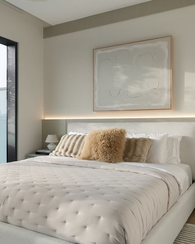 Neutral-toned bedroom with upholstered bed, textured pillows, and backlit artwork above headboard