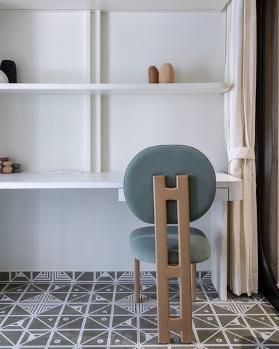 Sage velvet chair with wooden ladder back at white built-in desk on patterned floor tile