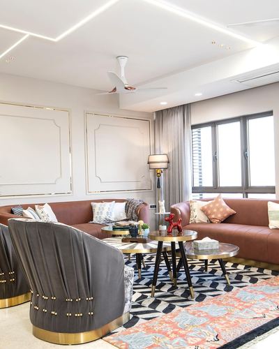 Living room with tan leather sofas, grey velvet chairs, gold accents and patterned rug