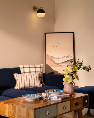 Navy velvet sofa corner with landscape print, terracotta vase and wooden drawer coffee table