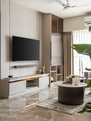 Beige living room with wall-mounted TV, fluted coffee table, and marble flooring