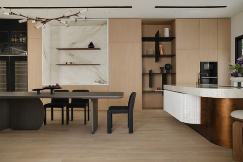 Open kitchen and dining area with oak cabinetry, marble niche, and curved bronze-fronted island