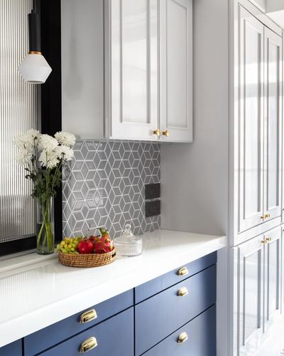 Kitchen corner with navy cabinets, white countertop, geometric grey tile backsplash and brass hardware