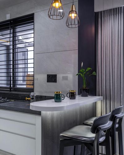 Grey-toned kitchen with curved white counter, ribbed metal base, cage pendant lights, black stools