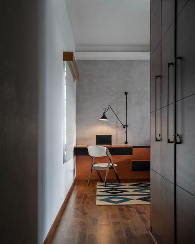 Small study nook with floating desk, swing-arm lamp, wooden chair and patterned rug