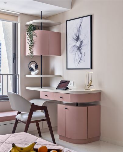 Curved pink desk and floating shelves in a beige study nook with framed abstract art
