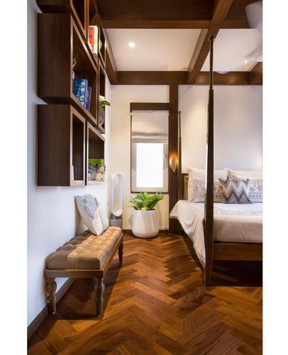 Bedroom with herringbone wood floor, four-poster bed, beamed ceiling and wall-mounted bookshelf