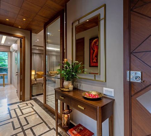 Wood-paneled entryway with mirror, console table, brass bowl and geometric marble floor