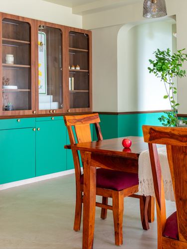 Dining nook with teal-and-wood cabinetry, wooden chairs and a red apple on the table