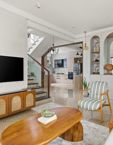 Open living room with cane TV console, organic coffee table, staircase, and view into kitchen
