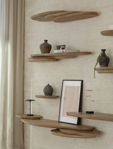Sculptural wood shelves with ceramics and framed art against a textured plaster wall