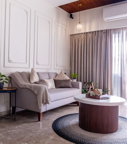 Living room with chevron-patterned sofa, fluted round coffee table, and floor-length curtains