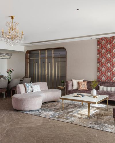 Living room with curved pink sofa, chandelier, and arched mirrored divider, Mumbai apartment