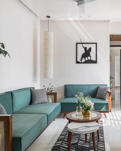Minimalist living room corner with teal sofas, wooden coffee tables, and horse rider wall art