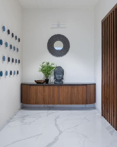 Foyer with fluted wood console, round mirror, buddha statue and marble-look flooring