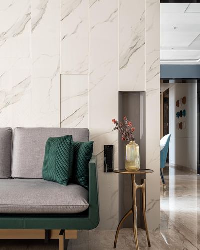 Grey and green sofa against marble wall with niche and gold side table