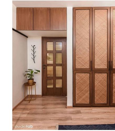 Foyer with wooden glass-paneled door, cane wardrobe shutters, and overhead wood cabinets