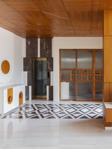 Elevator lobby with wood ceiling, dark marble cladding, and diamond-patterned marble floor