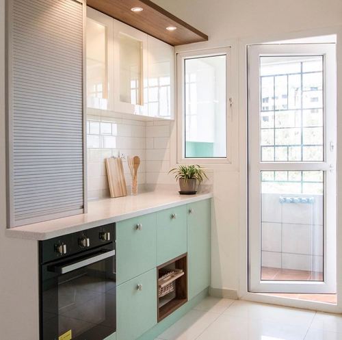 Small mint-green and white kitchen with subway tile backsplash and glass balcony door letting in daylight