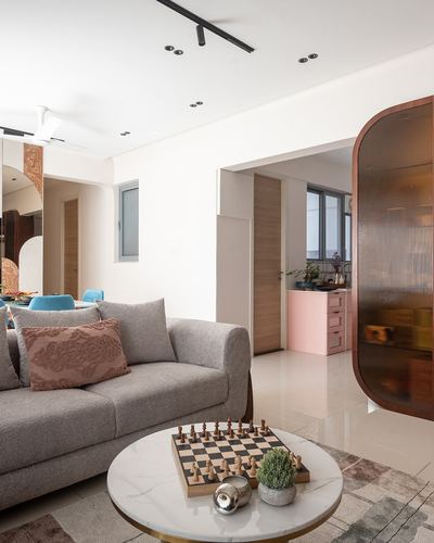 Living room with grey sofa, round marble coffee table with chessboard, curved fluted glass partition beyond