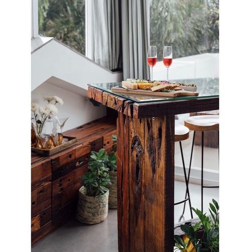 Reclaimed wood bar table with glass top on terrace, wine glasses and cheese platter